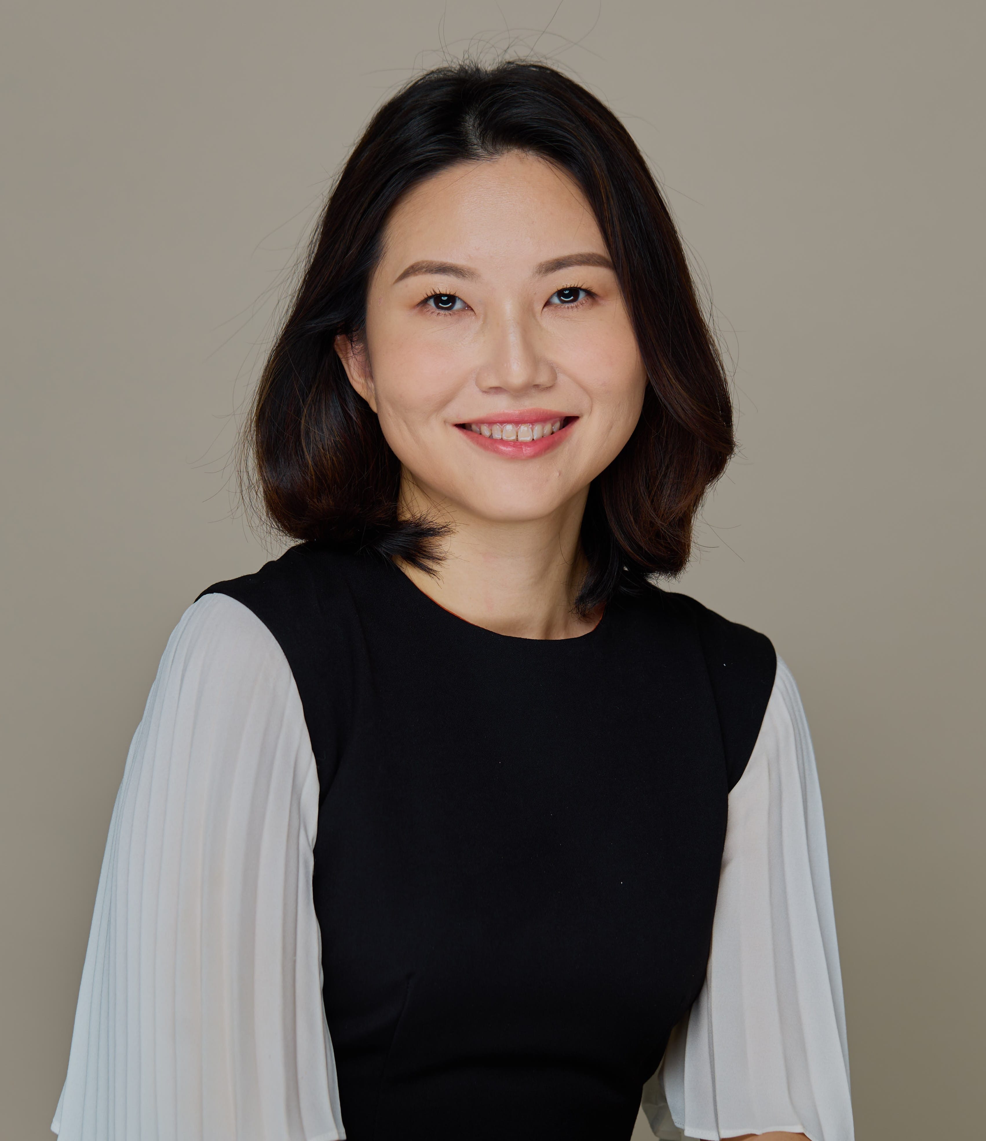Person smiling, with short dark hair, wearing a black and white dress.